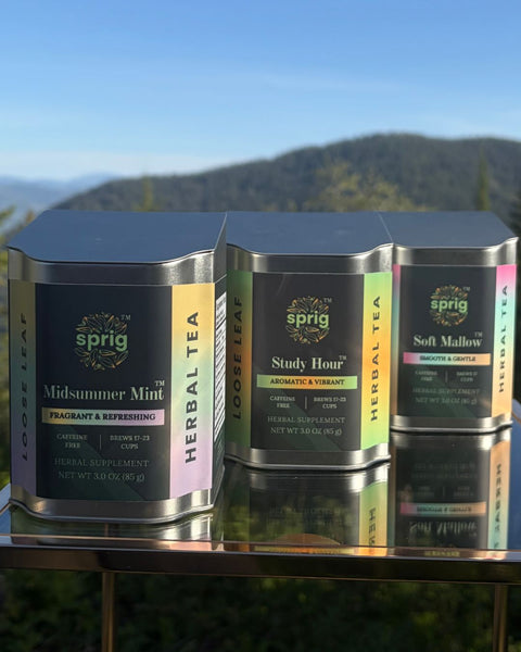 Midsummer mint, study hour, and soft mallow tea tins with a mountain background