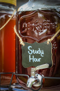 Large glass jug filled with brown colored brewed tea and labeled Study Hour